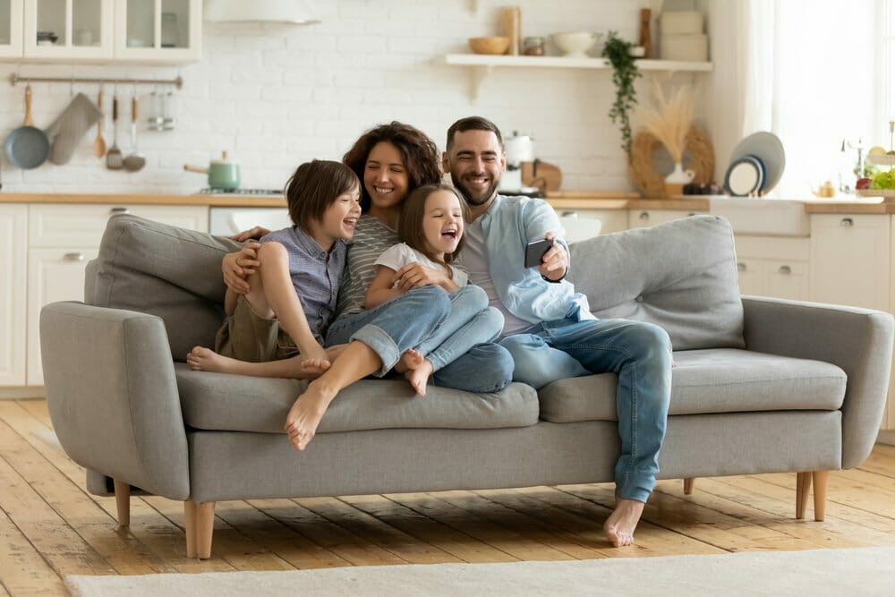 Miembros de una familia sentados en el sofá de su sala.
