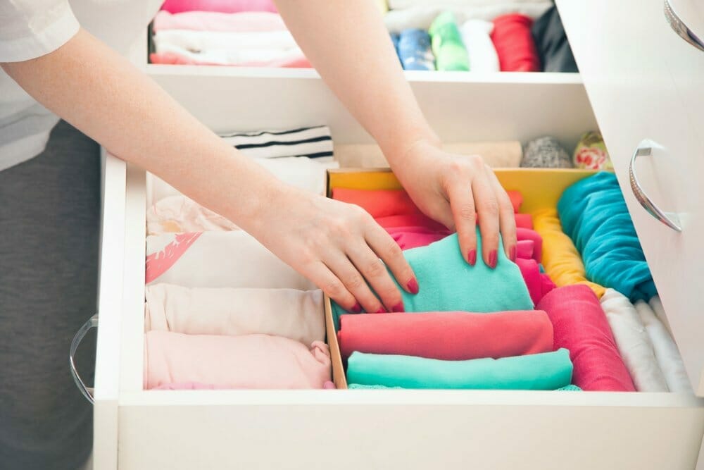 Mujer organiza su ropa en el cajón de su armario.