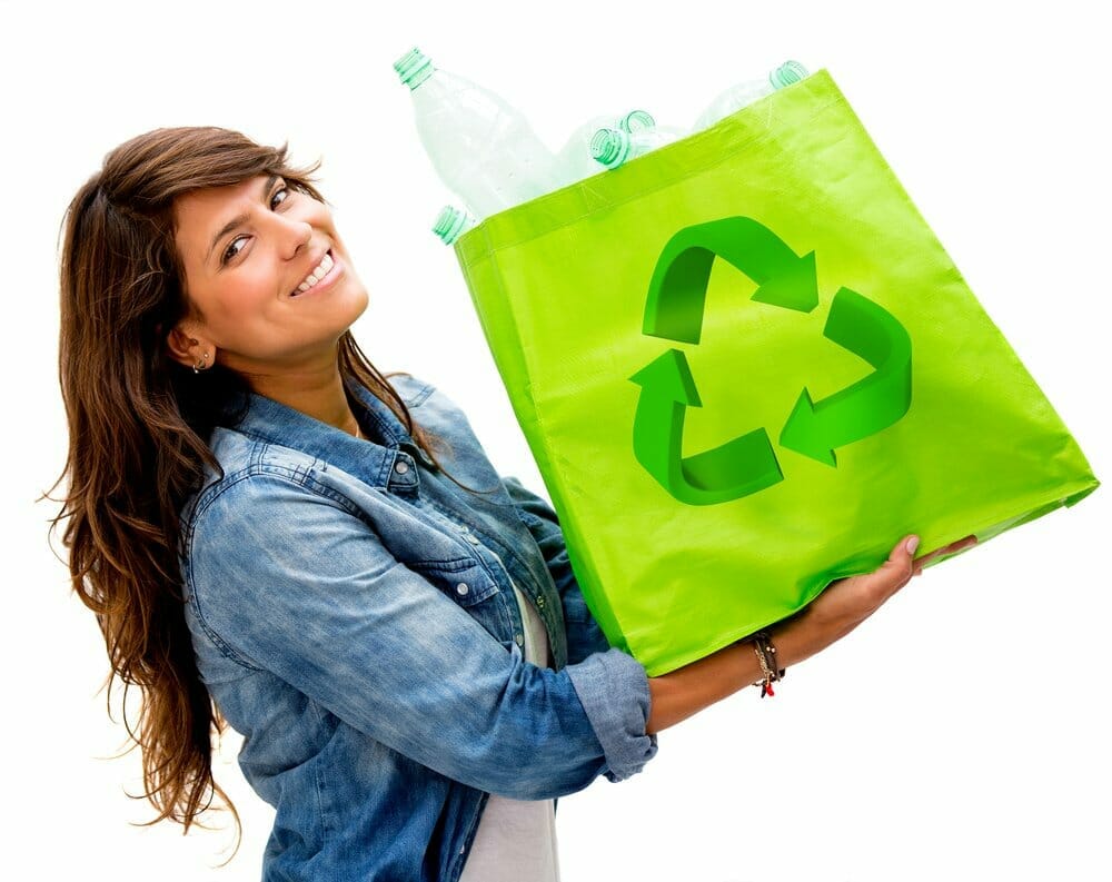 Mujer con una bolsa ecológica llena de botellas de plástico para reciclar.
