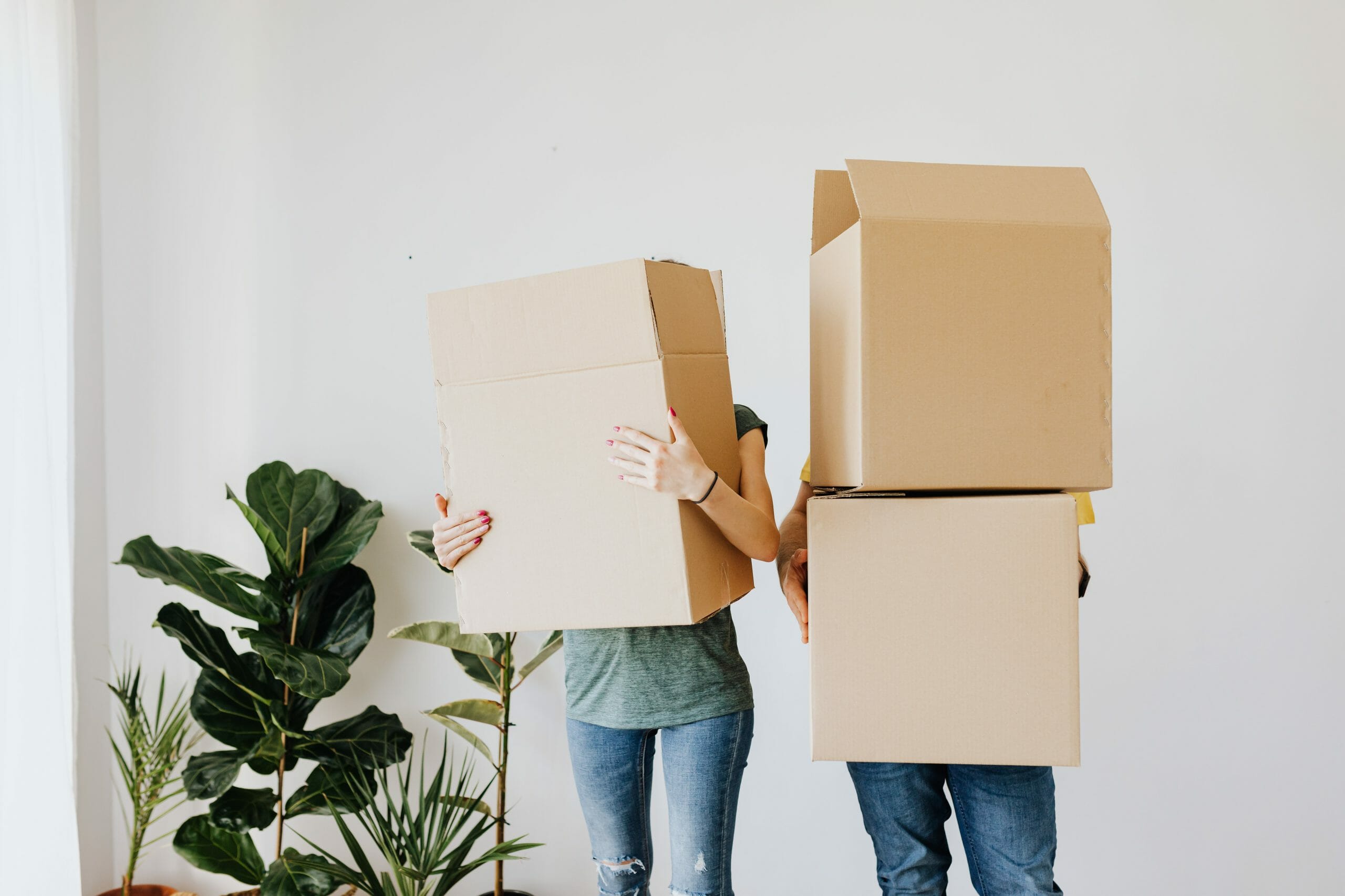 Pareja mudándose de casa con cajas de cartón que cubren su rostro