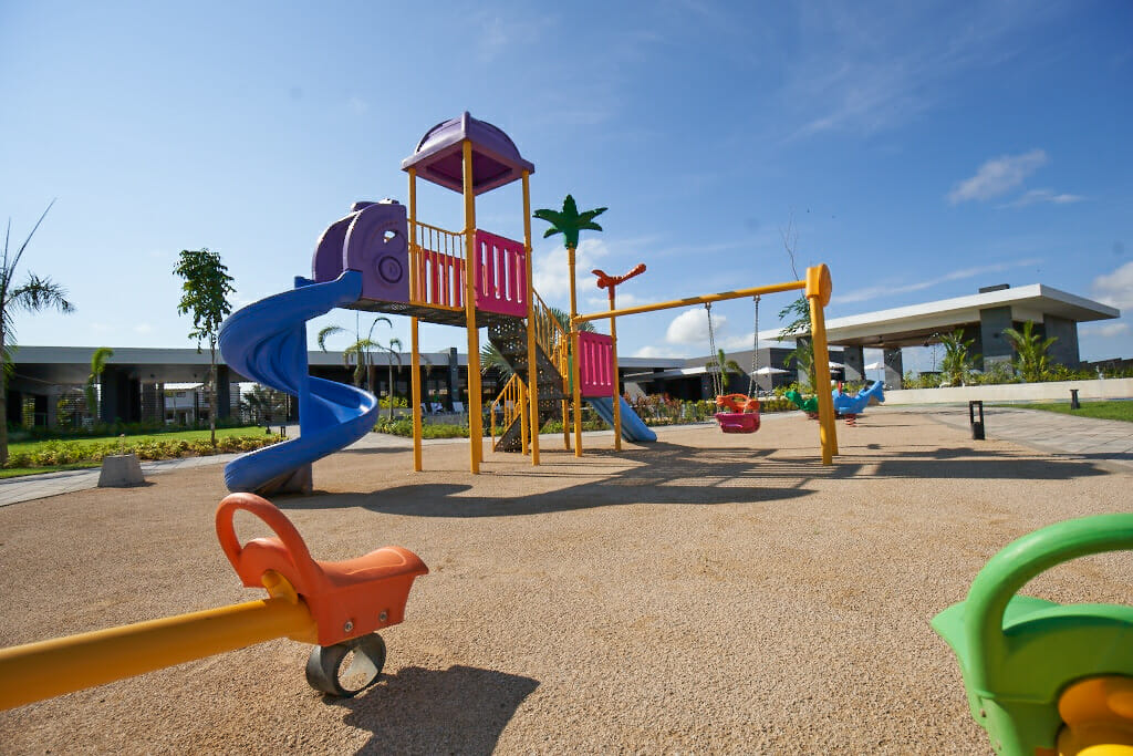 Parque infantil de diversiones con columpios, rodeado del área social del residencial