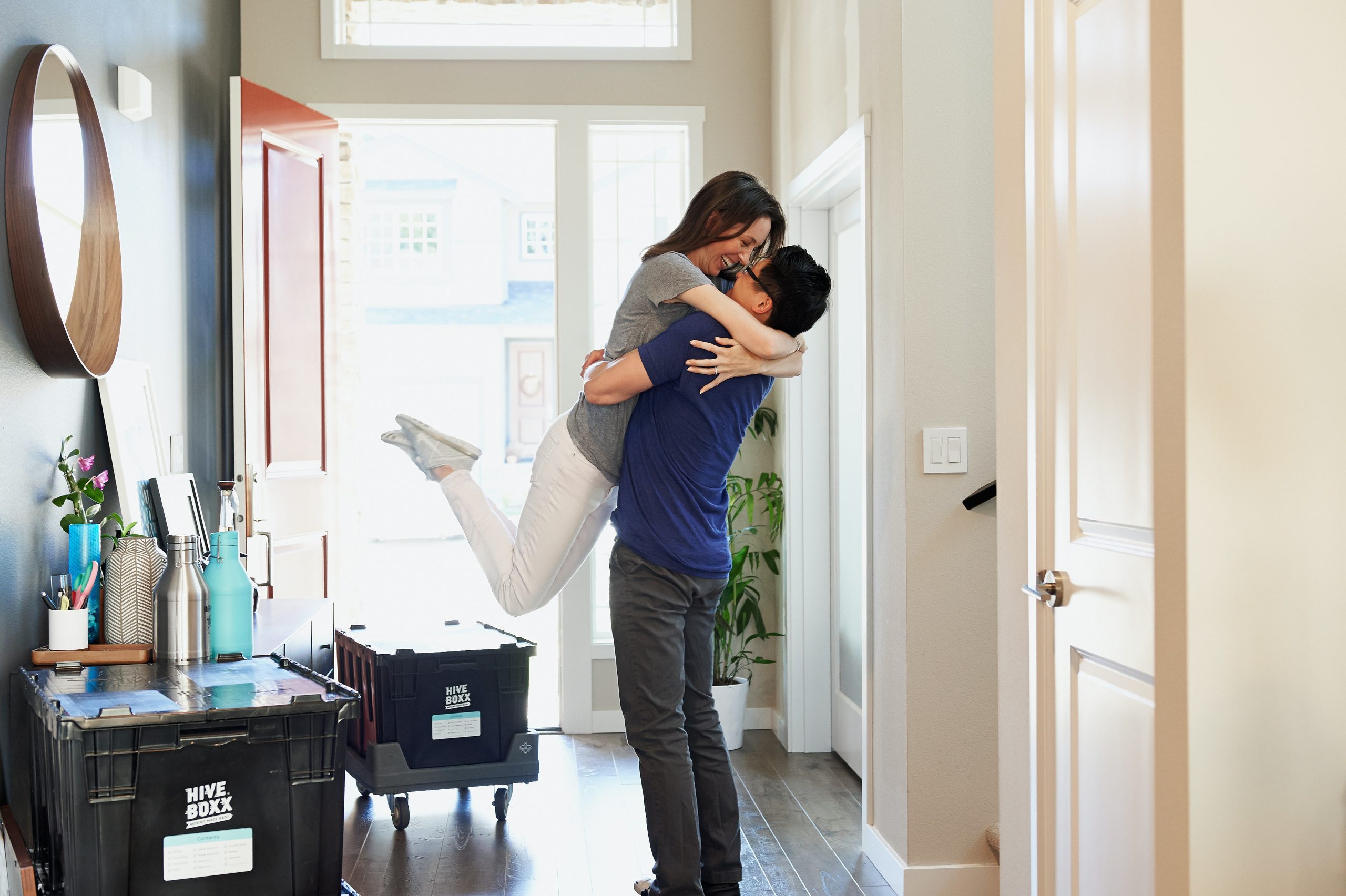 Pareja celebrando en recibidor mientras se muda a su nuevo hogar