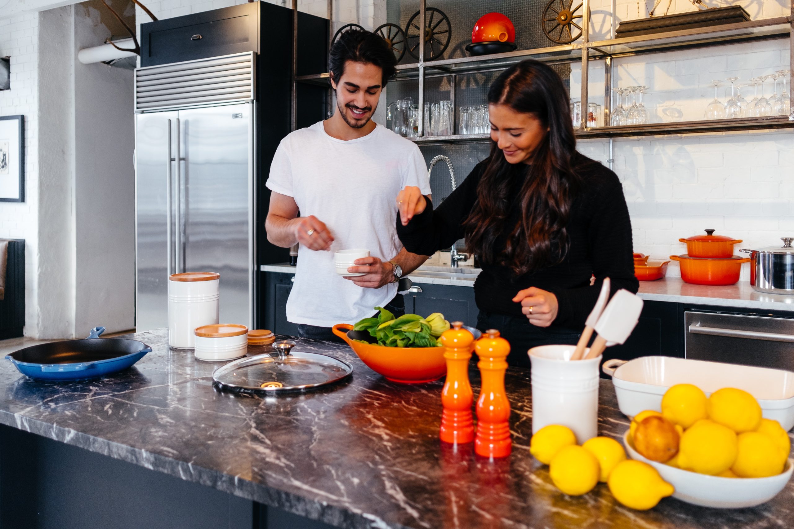 Dos compañeros de apartamento compartiendo mientras preparan alimentos en la cocina de su coliving