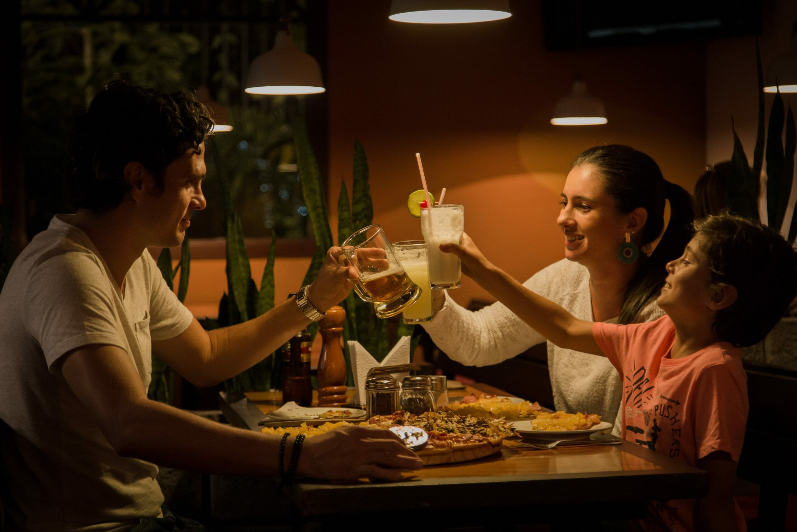 Familia de tres personas brindando y degustando platillos en un restaurante