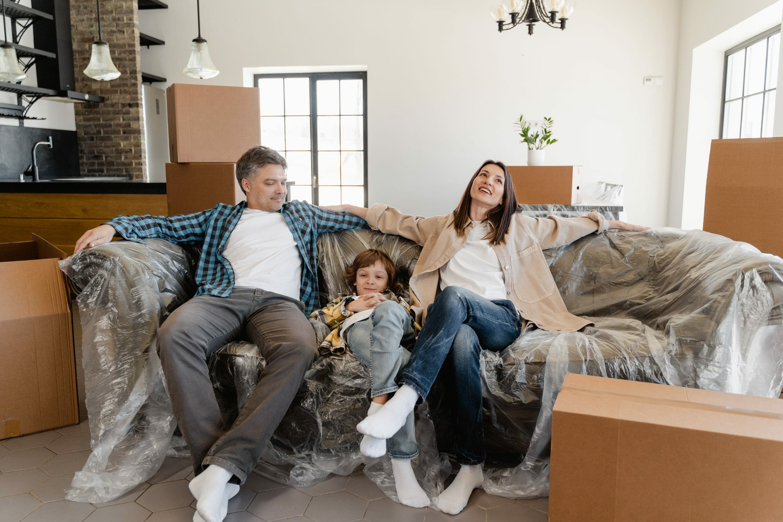 Familia relajándose en sillón en sala de su nuevo hogar mientras completan su mudanza