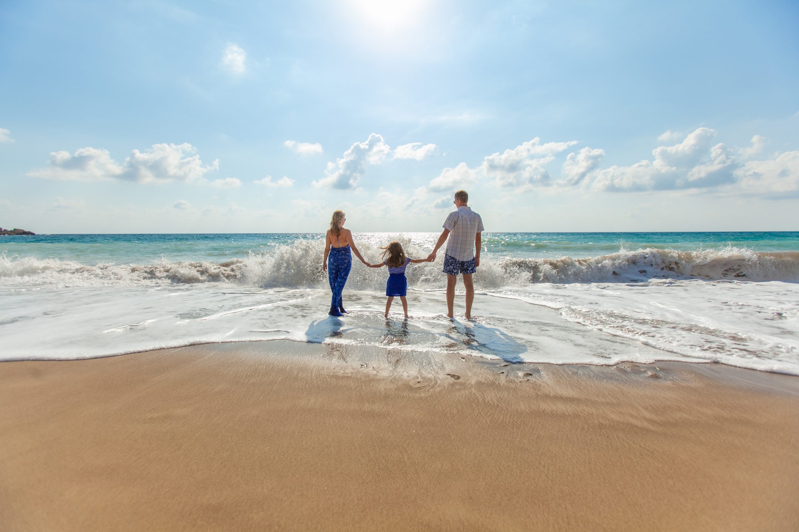 Familia de 3 personas mirando el atardecer en la playa.