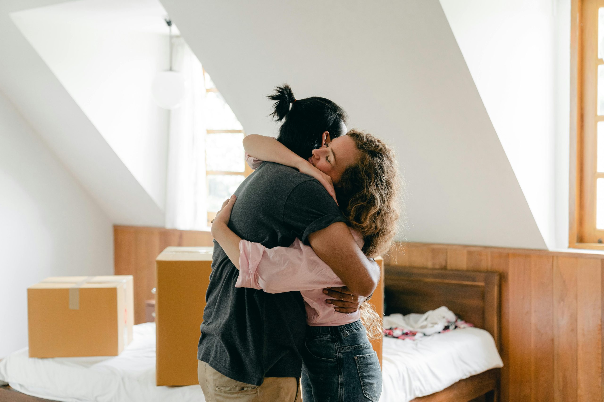 Pareja de esposos abrazándose mientras se mudan a su primera vivienda.