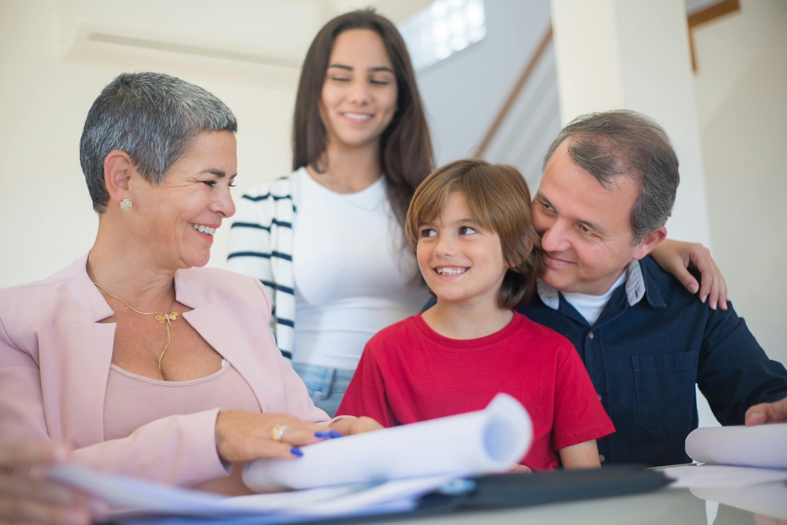 Familia analizando plan financiero con asesora de bienes raíces.