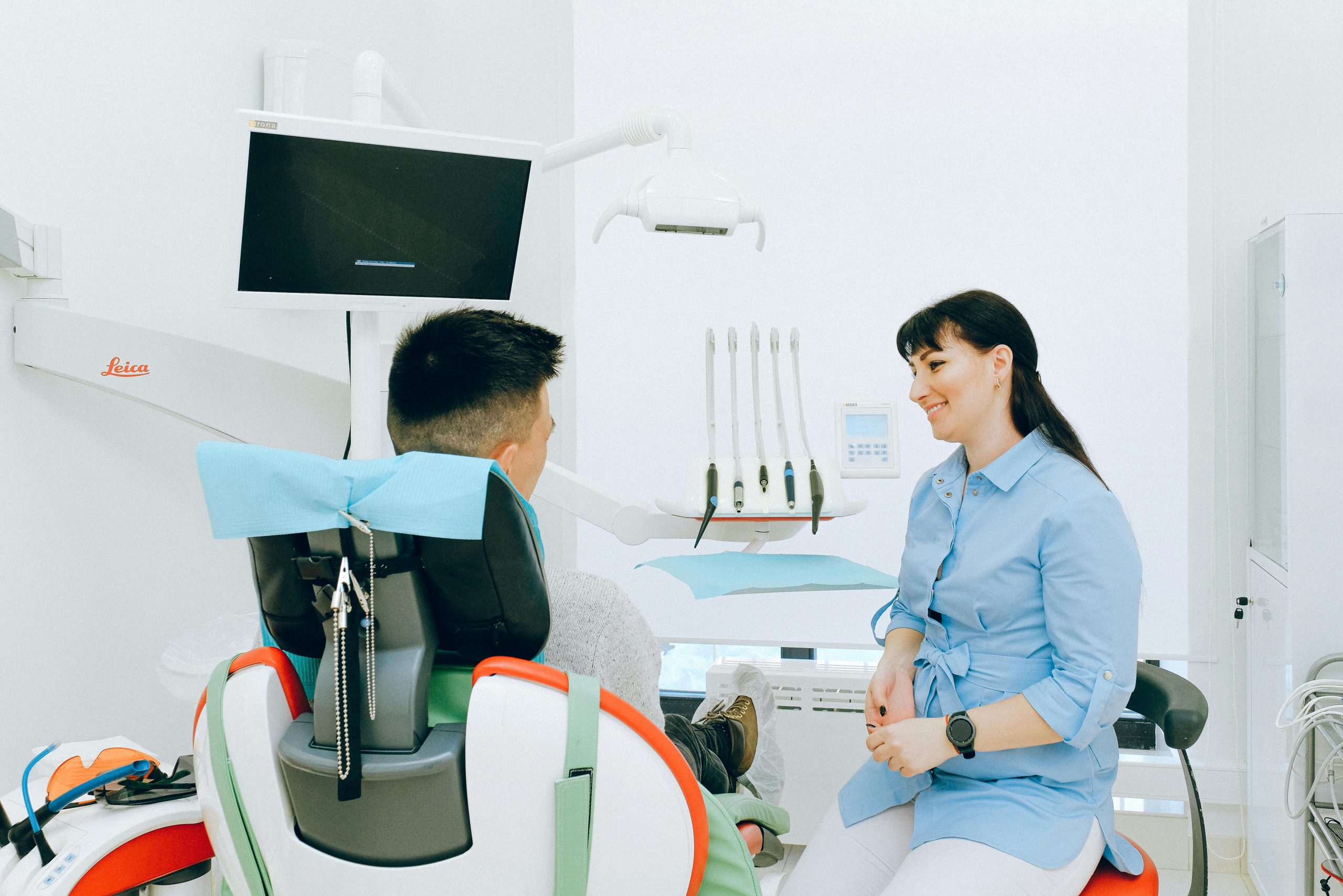 Dentista alegre hablando con el paciente sentado en una silla dentro de una clínica