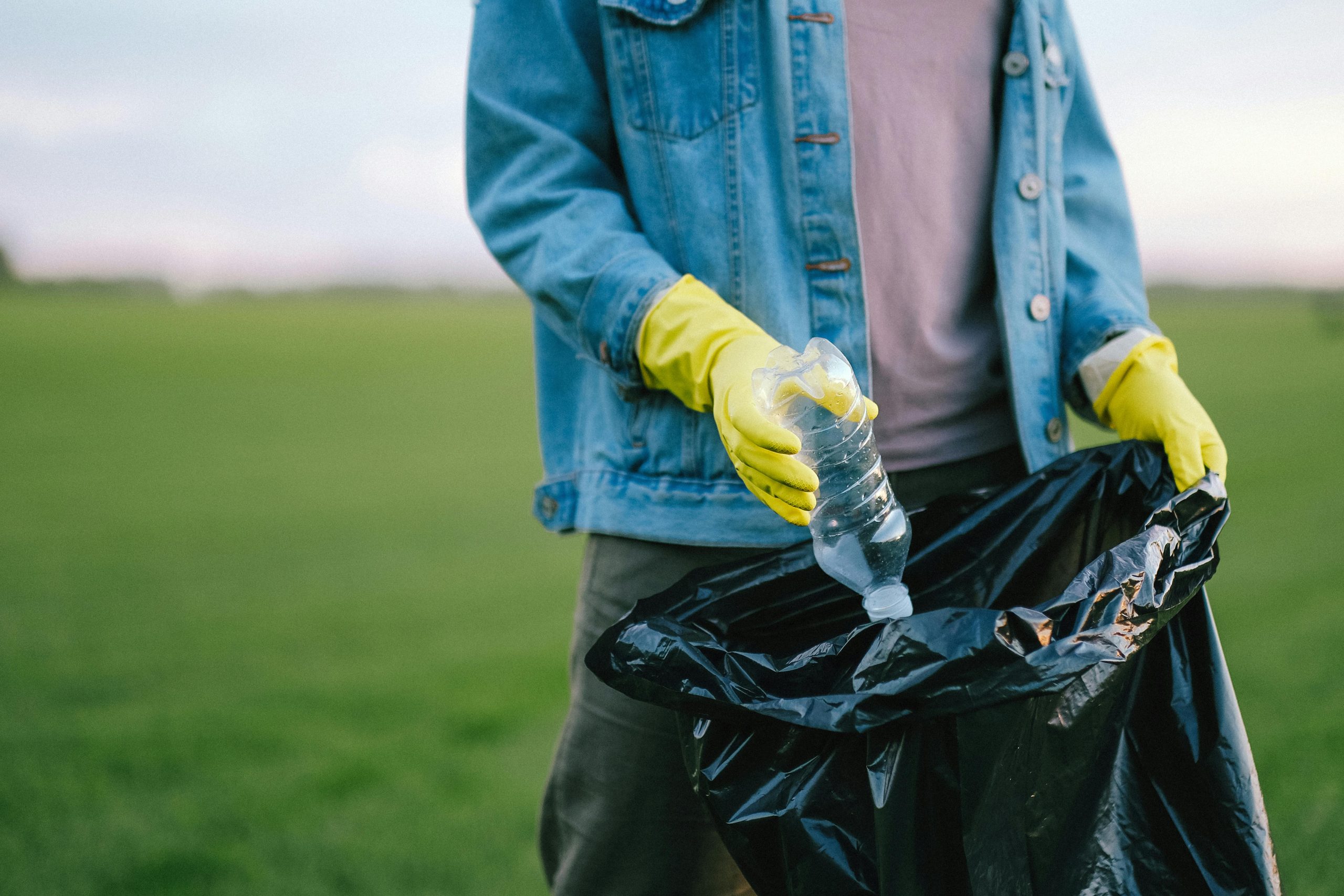 Voluntario depositando un desecho plástico en bolsa de basura.