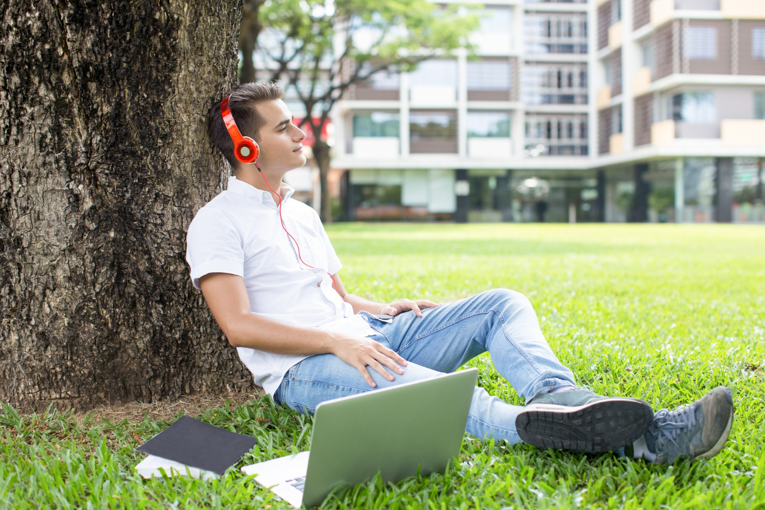 Joven con laptop y audífonos en un urbanismo cotidiano