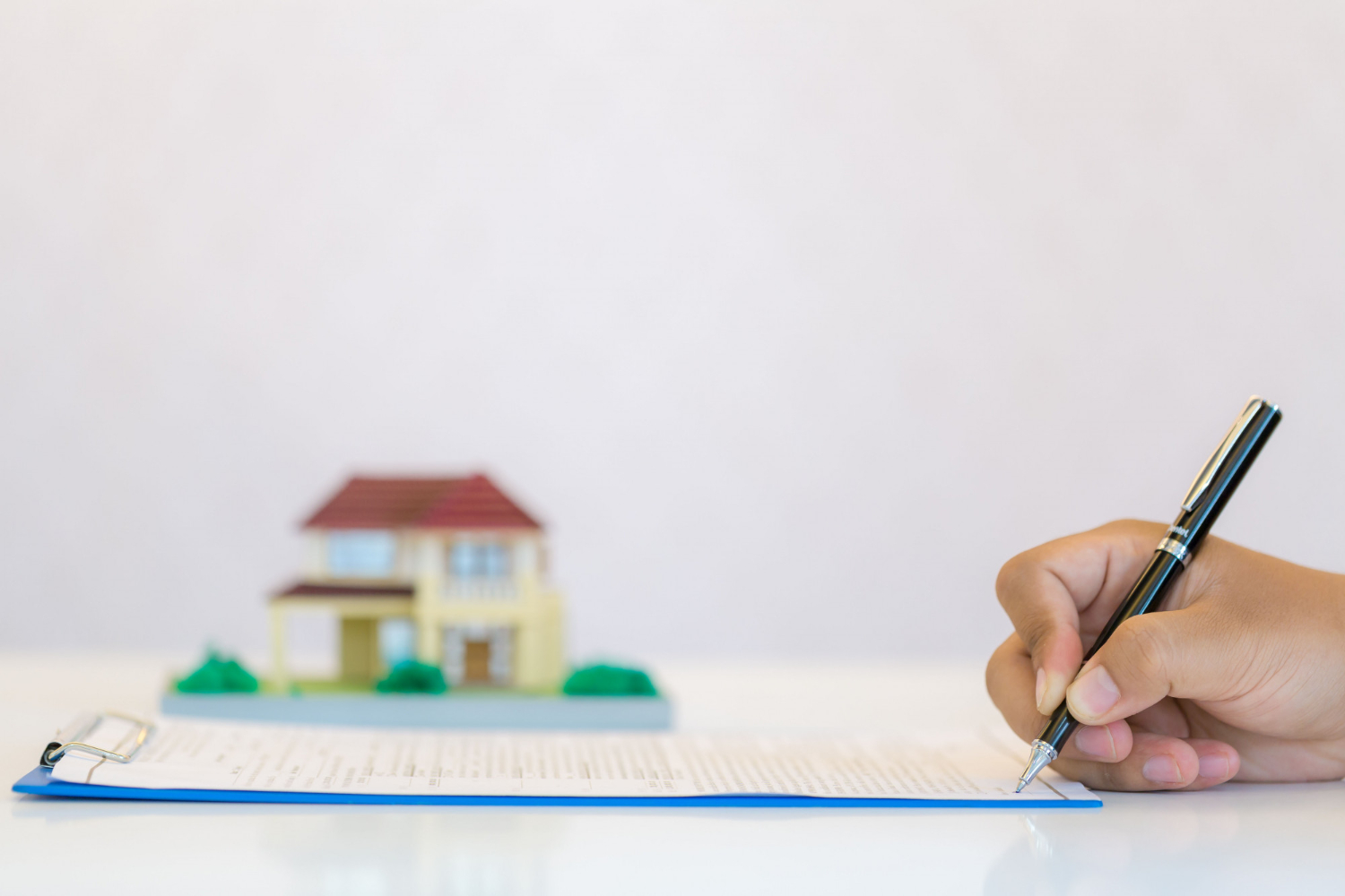 Firma de escritura ante notaría, manos firmando documentos legales de venta de inmueble