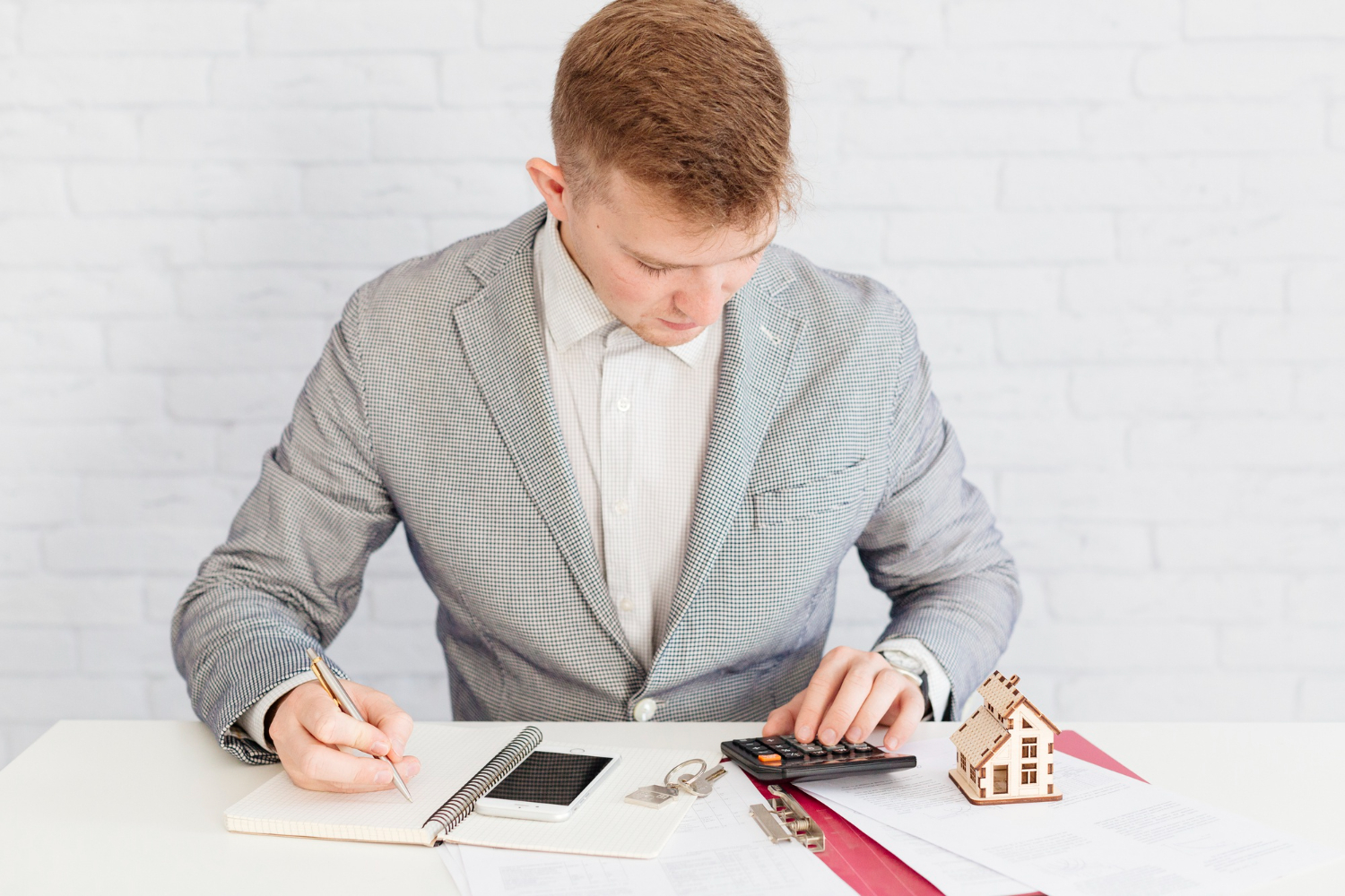 Persona revisando contrato de compraventa con calculadora y documentos, concepto de impuestos y cierre inmobiliario.