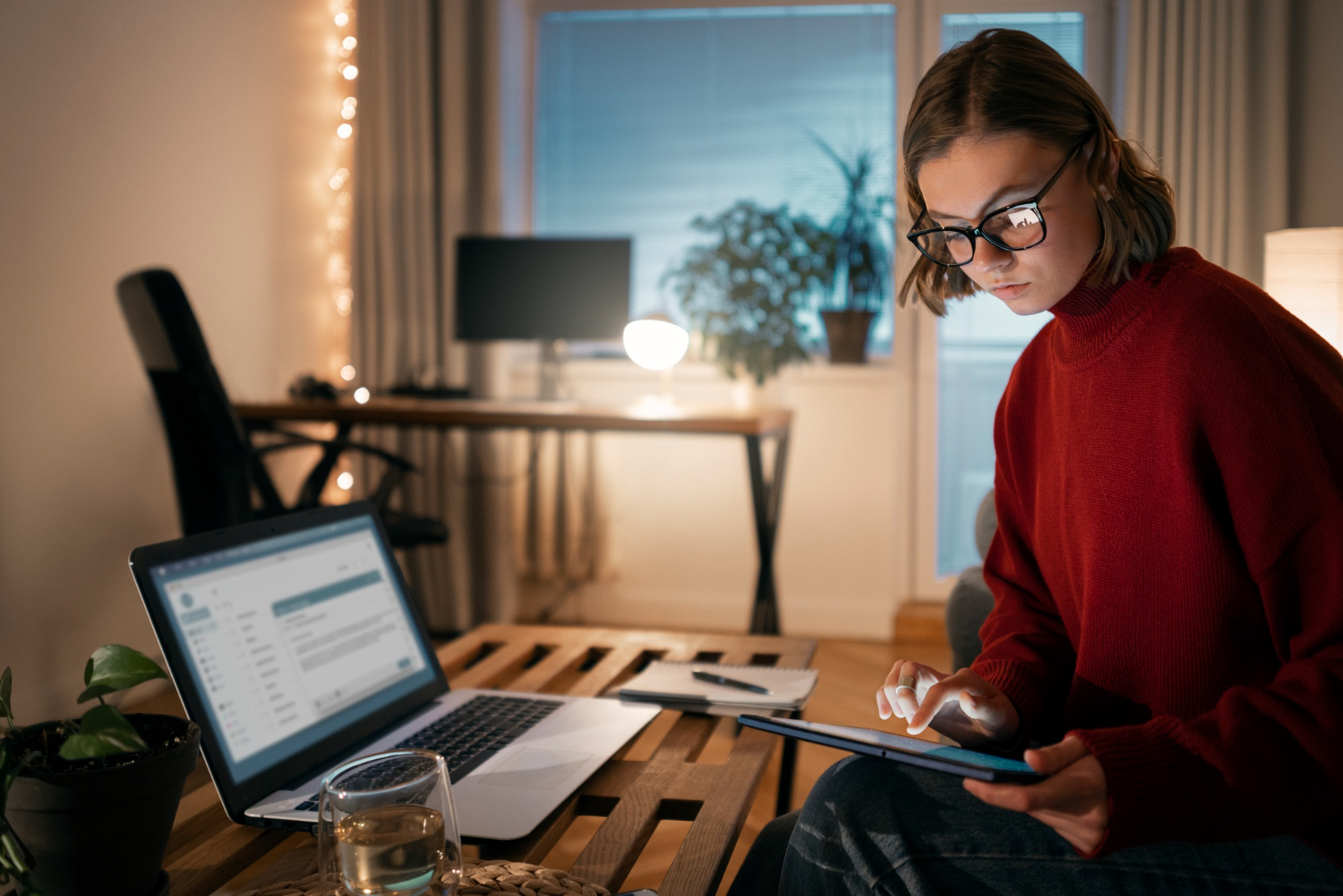 Persona trabajando de noche con laptop y notas financieras, planificando el pago de su futura casa 